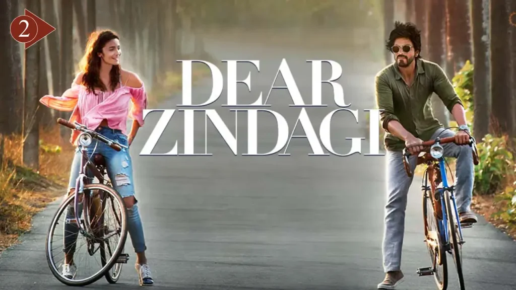 Alia Bhatt and Shah Rukh Khan riding bicycles on a tree-lined road in the Bollywood movie Dear Zindagi (2016) poster.